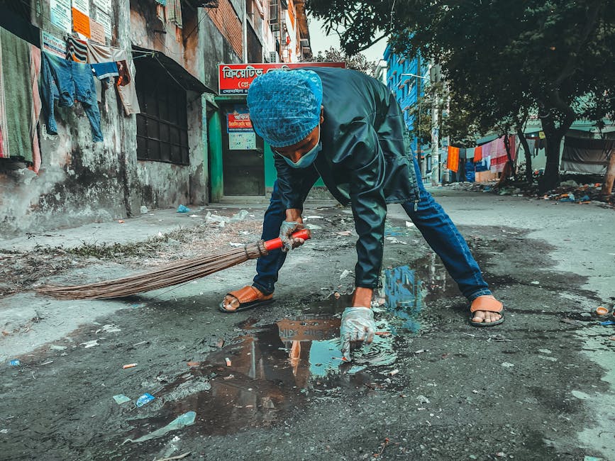 pexels-photo-12725831-12725831 A person wearing a mask and gloves cleaning the street in a Bangladesh neighborhood.