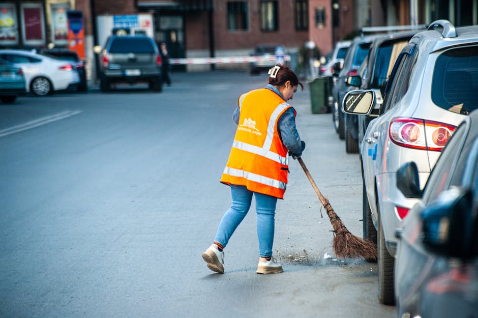 pexels-photo-31858860-31858860 A street cleaner in Tbilisi wearing a reflective vest sweeps debris from the roadside.